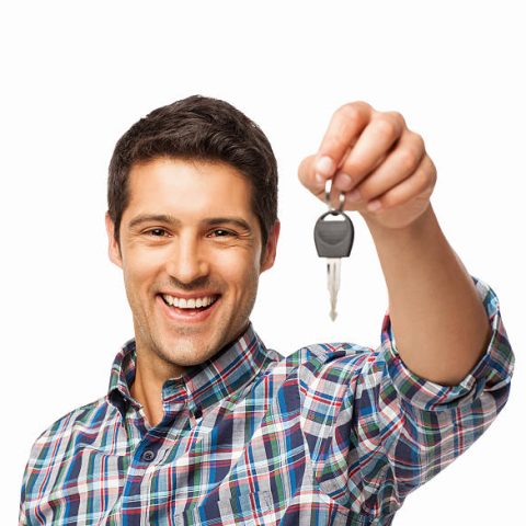 Portrait of a cheerful young man holding car key. Square. Isolated on white.